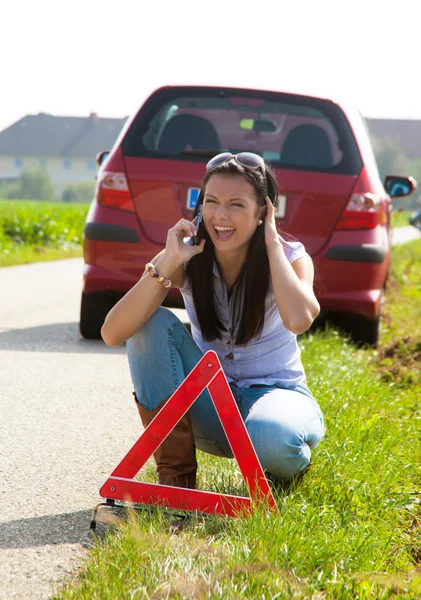 Mujer con un triángulo de advertencia en caso de avería — Foto de Stock