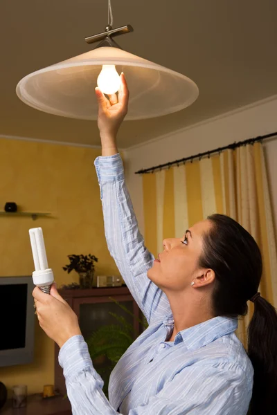 Jovem com lâmpada economizadora de energia — Fotografia de Stock