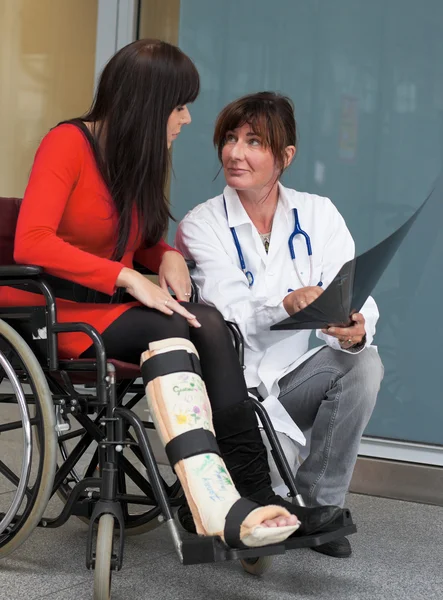 Žena s nohou v sádry, lékař a židle — Stock fotografie