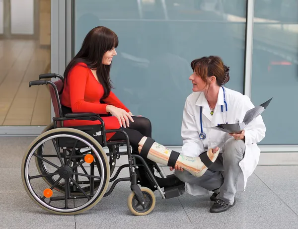 Femme avec jambe en plâtre, un médecin et une chaise — Photo