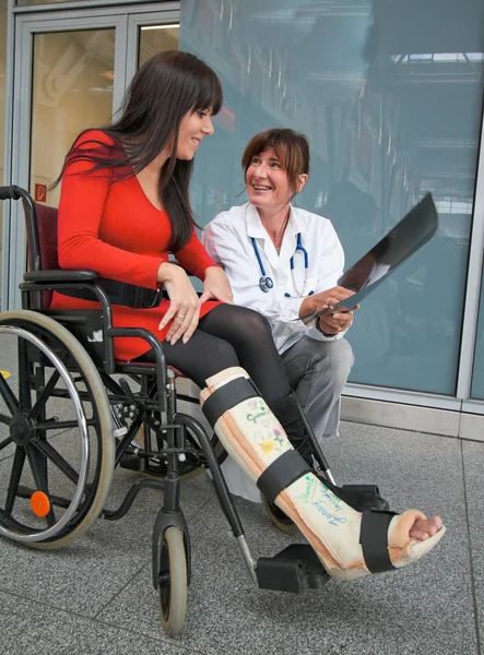Женщина с ногой в гипсе, врач и стул — стоковое фото