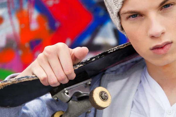 Cool-looking young man in front of graffiti — Stock Photo, Image