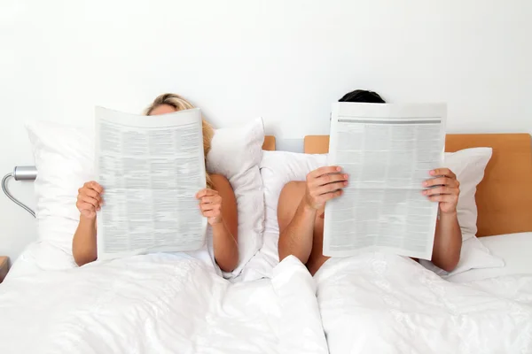 Par i sängen läsa tidningen — Stockfoto
