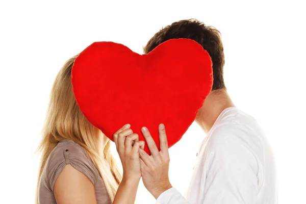 Casal apaixonado beijando atrás de um coração . — Fotografia de Stock