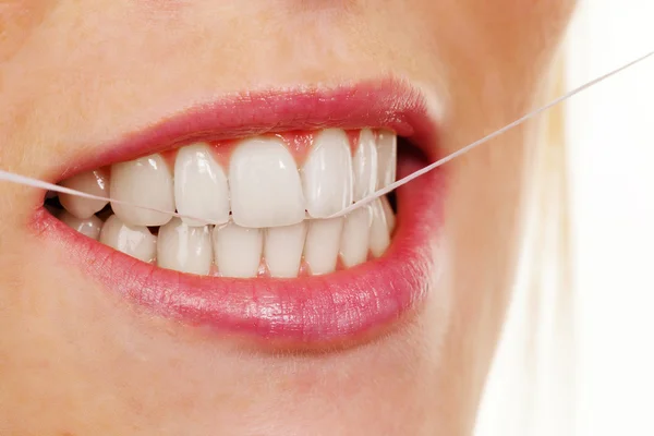 Женщина пользуется зубной нитью — стоковое фото