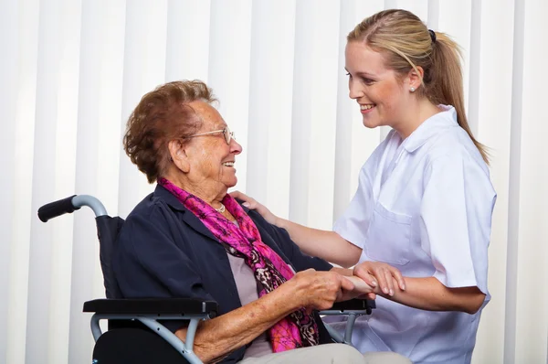 Enfermeira e a velha em uma cadeira de rodas — Fotografia de Stock