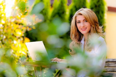 Woman with laptop in the garden clipart