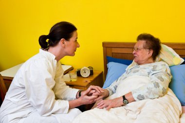 Sick old woman and nurse in a nursing home clipart