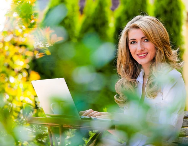 बगीचे में लैपटॉप कंप्यूटर के साथ महिला — स्टॉक फ़ोटो, इमेज