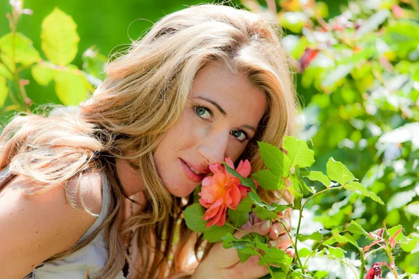Frau riecht eine Rose im Garten — Stockfoto