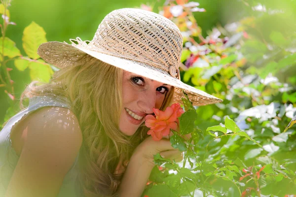 Mujer oliendo una rosa en el jardín —  Fotos de Stock