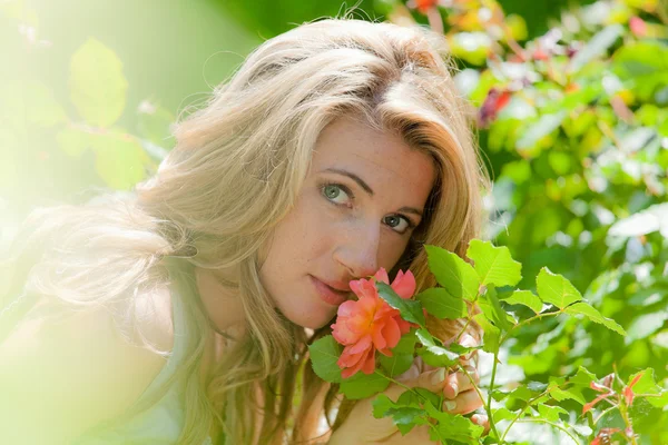 Femme sentant une rose dans le jardin — Photo
