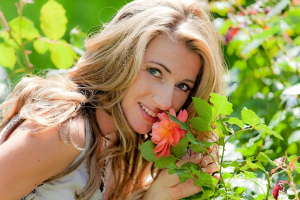 Žena voní růže v zahradě — Stock fotografie