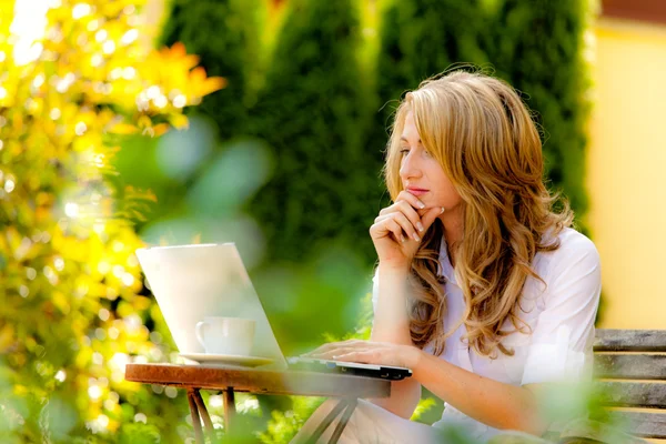 Жінка з ноутбуком в саду — стокове фото