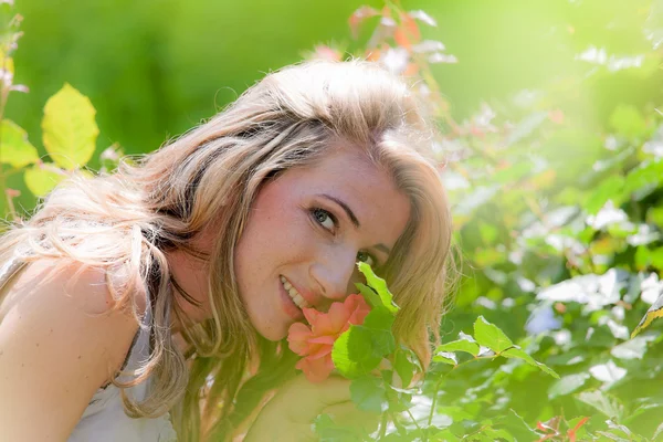 Женщина, пахнущая розой в саду — стоковое фото