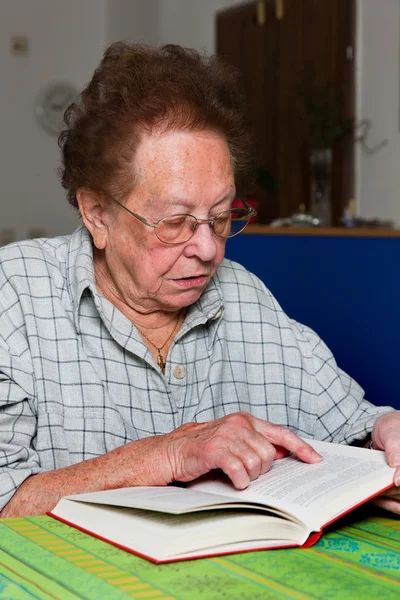 Ηλικιωμένη γυναίκα διαβάζει ένα βιβλίο με γυαλιά — Φωτογραφία Αρχείου