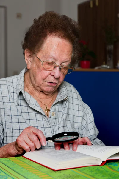 Seniorin liest Buch mit Brille — Stockfoto