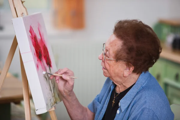 Elderly woman active in leisure time painting a picture — Stock Photo, Image