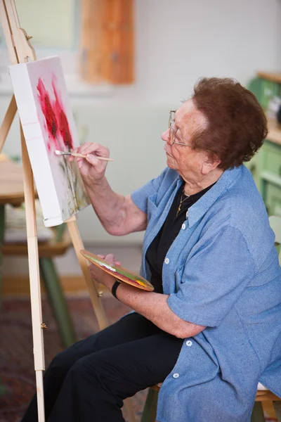 Пожилая женщина, активно занимающаяся досугом, рисует картину — стоковое фото