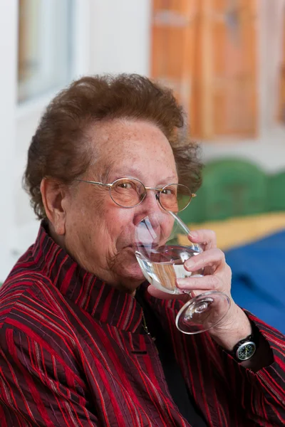 Äldre kvinna dricksvatten från ett glas — Stockfoto