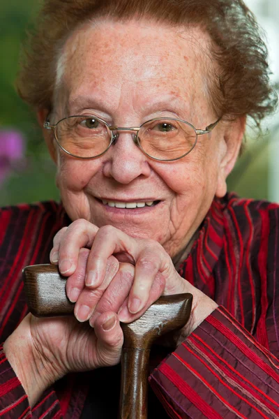 Behinderte ältere Frau mit einem Gehstock mit einem Lächeln — Stockfoto
