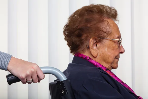Verpleegkundige en de oude vrouw in een rolstoel — Stockfoto