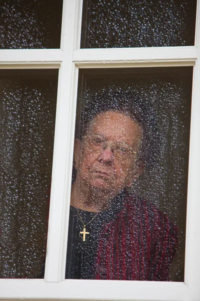 Gammal kvinna vid fönstret med regndroppar — Stockfoto