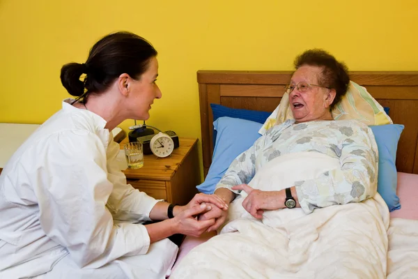Больная старуха и медсестра в доме престарелых — стоковое фото