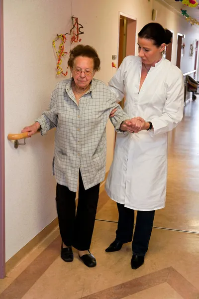Enfermeiras supervisionaram a mulher idosa em um lar de idosos — Fotografia de Stock