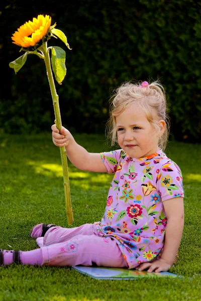 Kind met een zonnebloem in de tuin in de zomer — Stockfoto