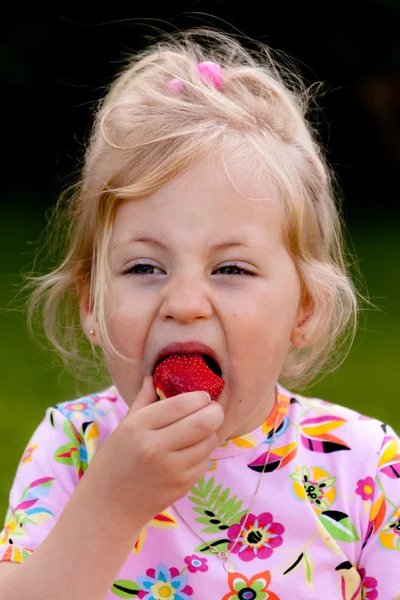 Παιδί που τρώει μια φράουλα στον κήπο — Φωτογραφία Αρχείου