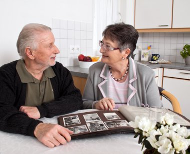 Glãƒâ ¼ ckliches elderly couple looks at photo album. clipart