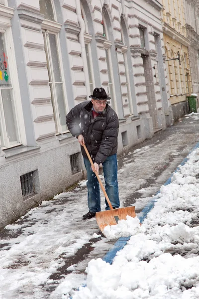 Hausmeister räumt Schneeglätte auf Gehweg ein — Stockfoto