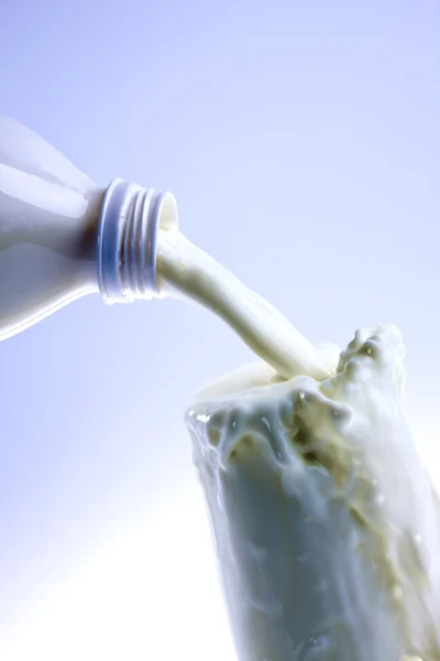 Pouring creamy fresh milk in a transparent glass — Stock Photo, Image