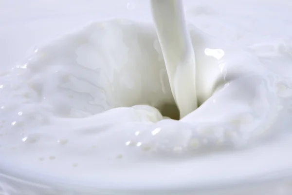 Pouring creamy fresh milk in a transparent glass — Stock Photo, Image