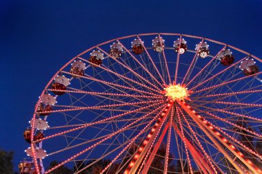 Ferris wheel at a carnival in the evening clipart