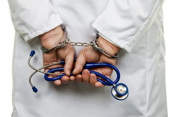 Доктор со стетоскопом и наручниками — стоковое фото