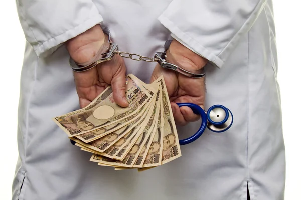 Doctor with japanese yen bank notes and handcuffs — Stock Photo, Image