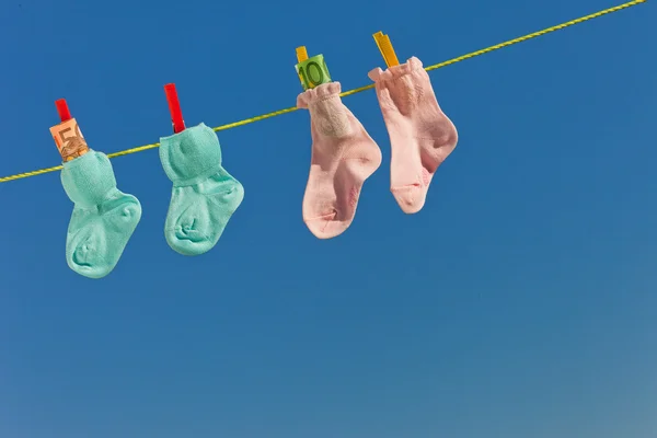 Chaussettes bébé sur corde à linge avec billets en euros — Photo