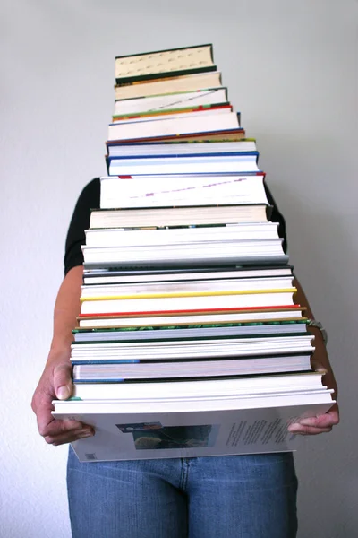 Einen schweren Stapel Bücher in Händen haltend — Stockfoto