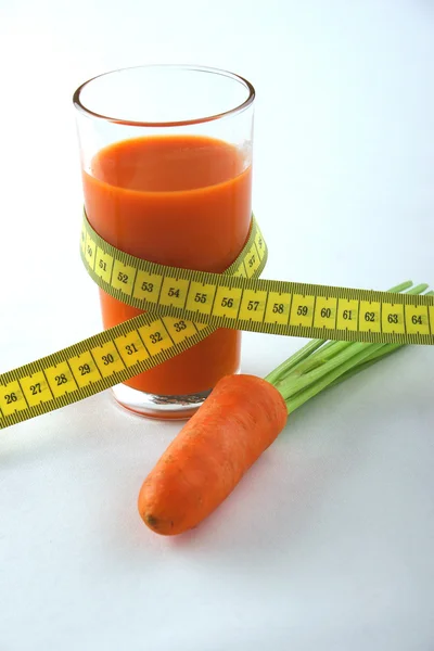 Fresh carrot juice in a glass, some carrots, measure tape — Stock Photo, Image
