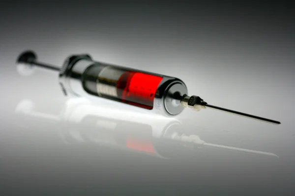 Filled syringe against gray background — 스톡 사진