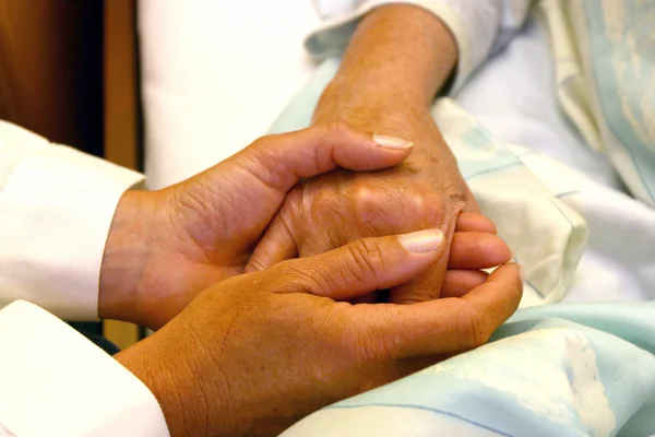 Doctor holding hands of patient — Stock Photo, Image