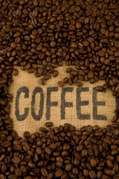 Этикетка кофе на мешковине и кофейных зерен — стоковое фото
