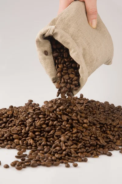 Рука з кавовими зернами та мішком — стокове фото