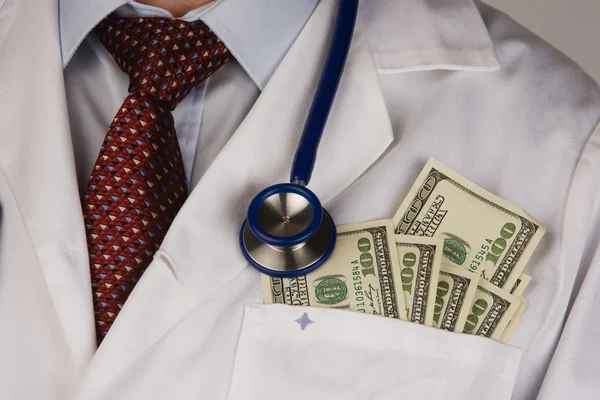 A doctor putting money in his pocket isolated on white background — Stock Photo, Image