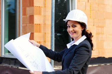 Architect with plan on construction site clipart