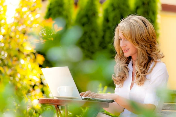Жінка з ноутбуком в саду — стокове фото