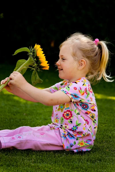 Niño con un girasol en el jardín en verano — Foto de Stock