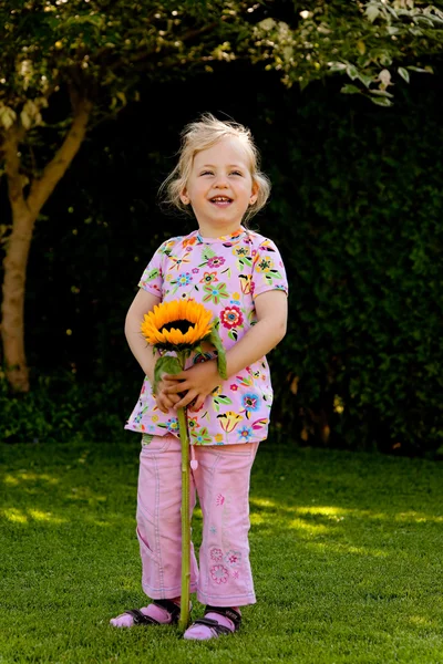 Παιδί με ένα ηλιοτρόπιο στον κήπο το καλοκαίρι — Φωτογραφία Αρχείου